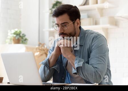 Pensive man work at laptop at home thinking Stock Photo