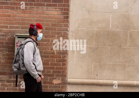 Montreal, CA - 16 May 2020: Young man with face mask for protection from COVID-19 waiting in line Stock Photo