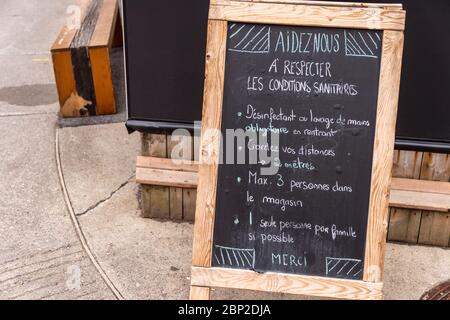 Montreal, CA - 16 May 2020: Guidelines and restrictions written in french on a chalkboard outside a store during the Covid-19 Pandemic Stock Photo