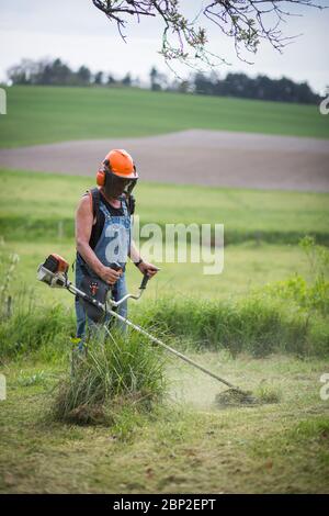 Landscaper using a thermal brush cutter. Stock Photo