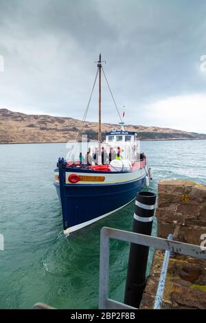 A small wooden ferry arriving at the small harbour at Kinloch on the Isle of Rum Scotland Stock Photo