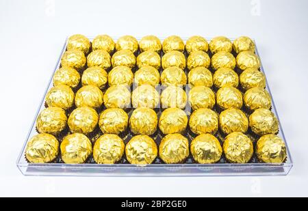 a lot of shiny golden chocolate wrapper in line on white background.. Stock Photo