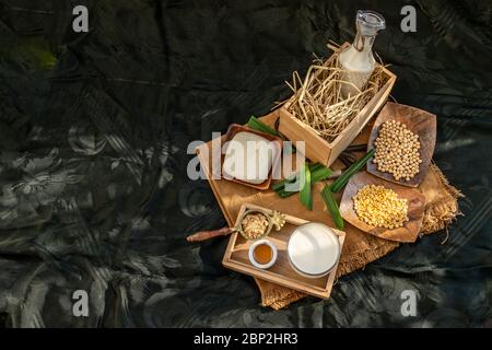 Soy products : A glass of Homemade soy milk and grains (soybeans) tofu Served with brown sugar and honey on sackcloth with lighting in the morning. Al Stock Photo