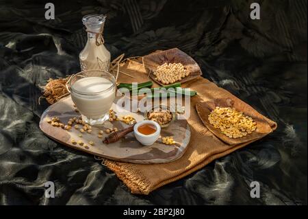Soy products : A glass of Homemade soy milk and grains (soybeans) Served with brown sugar and honey on sackcloth with lighting in the morning. Alterna Stock Photo