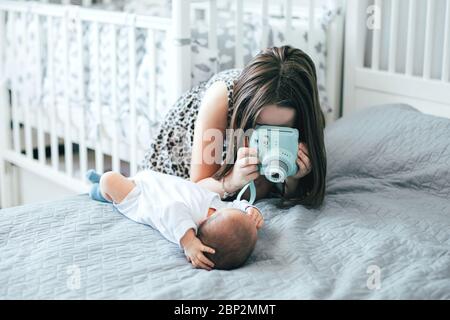 Older sister photographs the newborn's younger brother on bed in bedroomat home. Lifestyle family concept. Using technology concept Stock Photo
