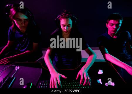 Group of young contemporary cybersports video gamers with headsets developing new game while one of them typing on keyboard Stock Photo