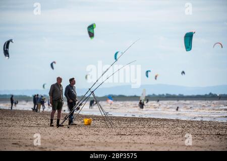 Fishermen on the beach at Weston-super-Mare with kite surfers in the background as Coronavirus restrictions are eased in England. Stock Photo