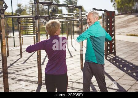 Sport activities in the early morning. Active mature family couple in sportswear exercising, doing sport together while standing at the stadium Stock Photo