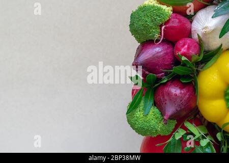 Multicolored arrangement of fresh vegetables with green leaves on the right side on a light beige background Stock Photo