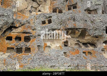 crypts cut into the cliff face  Otuzco archeological site, near Cajamarca, Peru               March Stock Photo