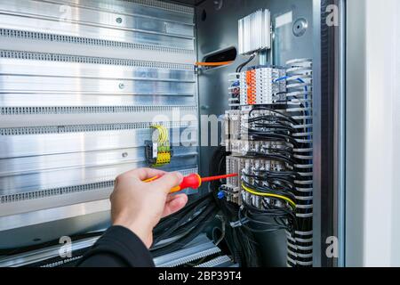 Electrical engineer checking electric cubicle and fixing connector strips. Stock Photo