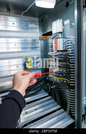 Electrical engineer checking electric cubicle and fixing connector strips. Stock Photo