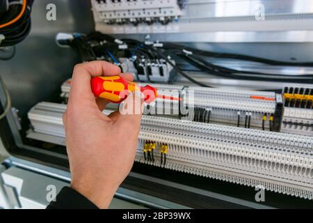 Electrical engineer checking electric cubicle and fixing connector strips. Stock Photo