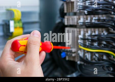 Electrical engineer checking electric cubicle and fixing connector strips. Stock Photo