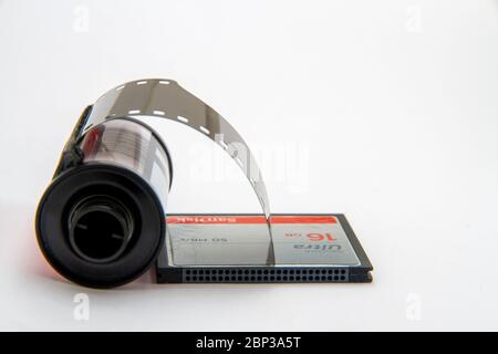 A 35mm film roll lies next to a 16GB sd card against a plain white background with space for text Stock Photo