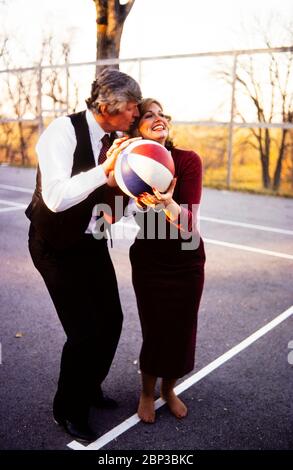 Phyllis George and new husband, Kentucky governor elect John Y Brown play a game of 'horse' on a basketball court at their home in Lexington. Brown is trying to distract his new bride by kissing and blowing in her ear. Phyllis Ann George was an American businesswoman, actress, and sportscaster. She was also Miss Texas 1970, Miss America 1971, and the First Lady of Kentucky from 1979 to 1983. Ms. George died, aged 70, of complications from Polycythemia vera on May 14, 2020 in Lexington, Kentucky. Stock Photo