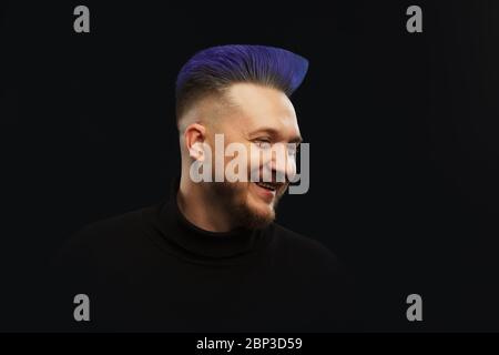 Man with blue or teal hair over dark background. Stock Photo