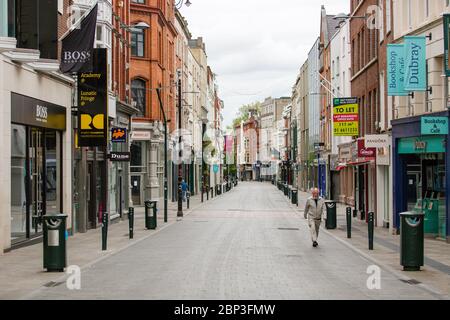 Senior man walking through deserted Grafton Street in Dublin City Centre as the footfall plummets due to coronavirus pandemic. Covid-19 in Ireland. Stock Photo