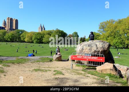 People social distancing in New York Central Park Sheep Meadow with a NYC Parks department six foot social distancing sign in the foreground. Stock Photo