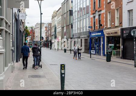 Pedestrians strolling through a deserted Grafton Street in Dublin City Centre as the shops remain closed due to coronavirus pandemic restrictions. Stock Photo