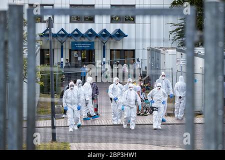 Sankt Augustin, Germany. 17th May, 2020. Officials of the police and the public order office go in protective suits to a refugee accommodation. In a refugee facility in St. Augustin (Rhein-Sieg-Kreis), 70 people have tested positive for the coronavirus. This was announced by the Cologne District Government on Sunday. A total of 300 persons were tested in the accommodation. Credit: Marcel Kusch/dpa/Alamy Live News