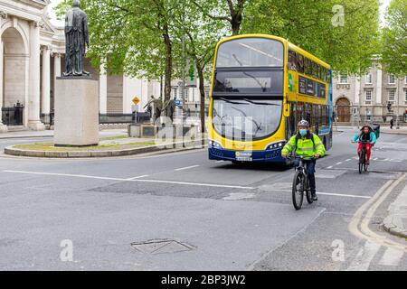 Cyclist wearing protective face mask and Dublin bus going through College Green in Dublin City Centre. Covid-19 pandemic restrictions. Stock Photo