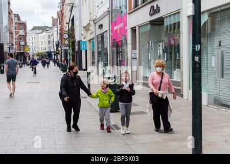 Family walking through a quiet Grafton Street in Dublin City Centre as the footfall plummets due to coronavirus pandemic. Civid-19 in Ireland. Stock Photo