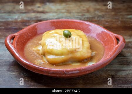 Portuguese francesine sauce poured in an earthenware dish. Stock Photo