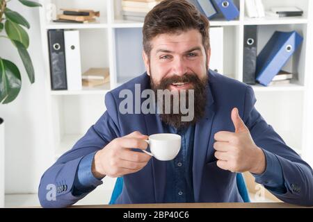 My energy. Man handsome boss sit in office drinking coffee. Comfy workspace. Good morning. Bearded hipster formal suit relaxing with coffee. Office life routines. Respectable ceo. First coffee. Stock Photo