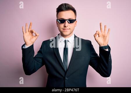 Young handsome caucasian business man wearing funny thug life glasses relax and smiling with eyes closed doing meditation gesture with fingers. Yoga c Stock Photo