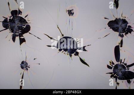 close-up view of physically damaged lcd screen surface with multiple separated impact spots, radial cracks, pixel grid leakage and discoloration Stock Photo