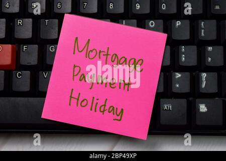Mortgage Payment Holiday write on sticky note isolated on wooden table. Stock Photo