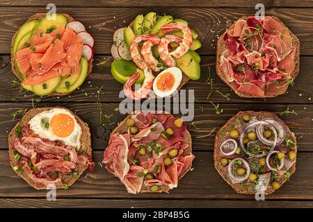 Six Danish traditional smorrebrods served with different meals are in wooden background Stock Photo