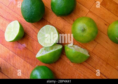 Juiced limes cut in half on a wooden cutting board; squeezed or reamed for juicing. Stock Photo