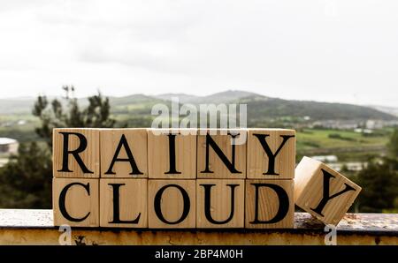 Cloudy, and, rainy, text on wooden cubes on rusty white painted iron. Stock Photo