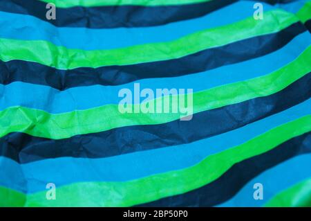 Closeup of a parallel striped paper of black, green, blue colors that is somewhat wrinkled Stock Photo