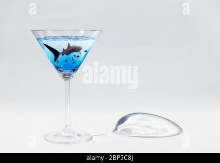 Sharktini: profile of whale shark (Rhincodon typus) swimming with black jacks (Caranx lugubris) in a martini glass on white background, Pacific Ocean Stock Photo