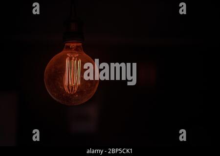 Light bulb glowing in dark room Stock Photo