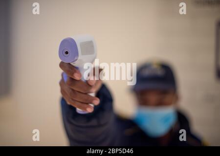 Man holding infrared thermometer with blurred background Stock Photo