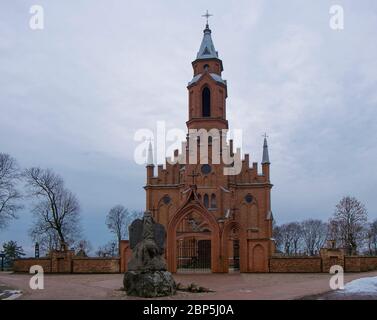 The Gothic style, red brick, Catholic church Svc. Mergeles Marijos Skaplierines Baznycia in the town of Kernave  In Lithuania. A stone statue of Moses Stock Photo