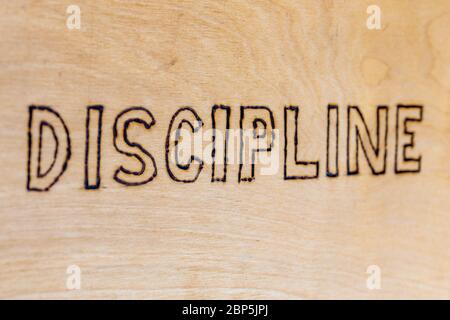 the word discipline burnt on white flat wooden surface - directly above normal view Stock Photo