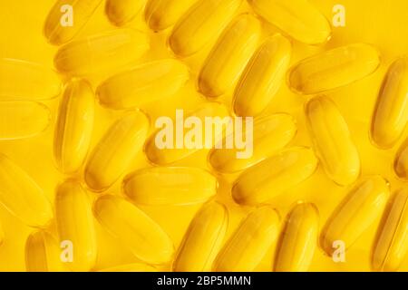 Close up of Omega 3 fish oil supplement product capsules isolated on yellow background. Stock Photo