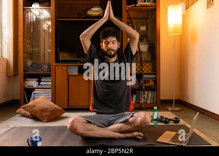 Young Hispanic man practicing yoga at home. Home yoga concept. Stock Photo