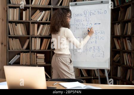 Female latin indian math school teacher student writing equation on whiteboard. Stock Photo