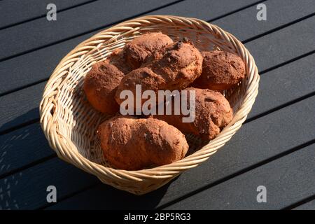 homemade fresh oblong grain rolls in wooden basket on black board Stock Photo