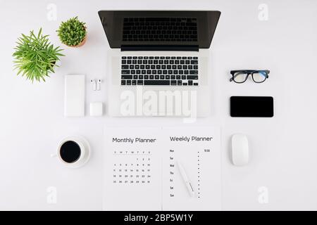 Planners, gadgets and cup of black coffee on table of office worker, view from the top Stock Photo