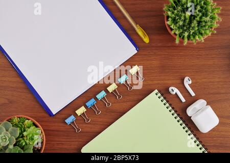 White empty sheet, textbook, wireless earbuds and paper clips on table of student, view from above Stock Photo