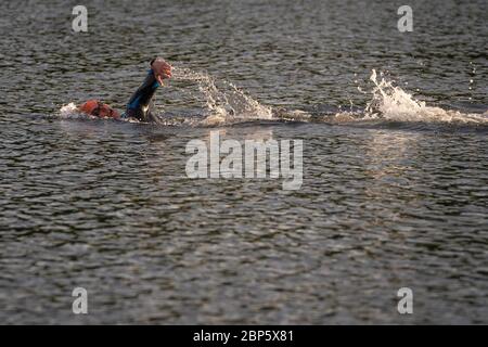 A swimmer takes an early morning swim at the Serpentine Lido in Hyde Park, London, as it re-opens to members of the Serpentine Swimming Club after the easing of coronavirus lockdown measures. Stock Photo