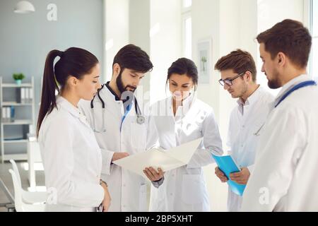 A team of doctors in a meeting discusses the diagnosis of a patient in a clinic office. Stock Photo