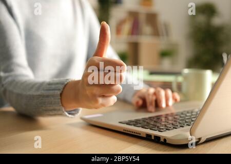 Close up of woman hands with thumbs up using laptop at night at home Stock Photo